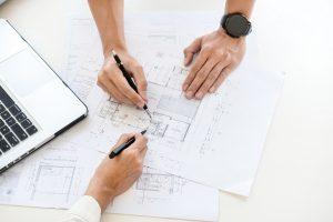 deux hommes discutant autour d'un bureau sur lequel sont disposés des plans