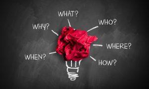 papier rouge froissé sur un tableau noir avec les mots « quoi, qui, où, pourquoi, quand" écrit à la craie