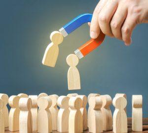 Un recruteur tient un aimant et attire des silhouettes en bois représentant des candidats