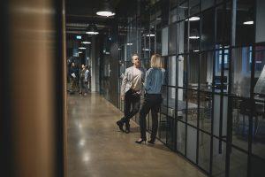 2 collaborateurs discutent dans le couloir d'une entreprise