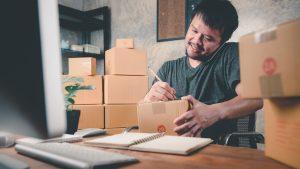 un homme concluant une vente au téléphone et préparant les colis pour expédition