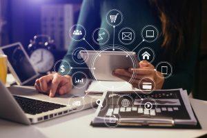 Femme travaillant avec un smartphone, un ordinateur portable et une tablette numérique dans un bureau avec des supports de marketing numérique sous forme d'icônes virtuelles