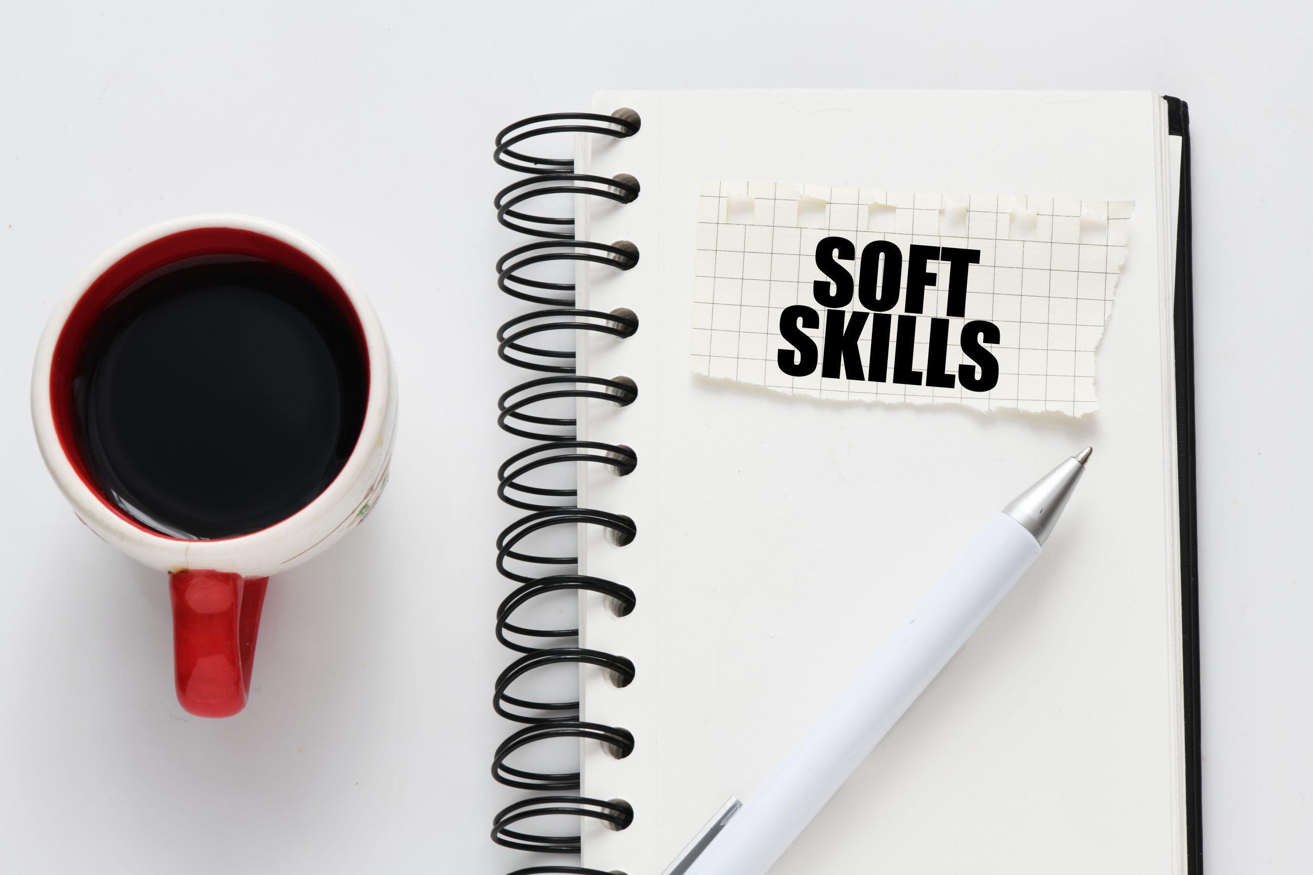 visuel des mots soft skills écrit sur un cahier à spirales, un stylo et un mug de café